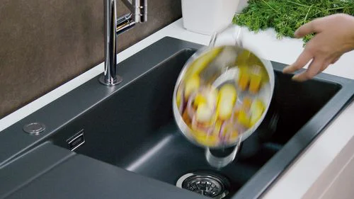 Das Wasser eines Topfes mit Kartoffeln wird in einem Keramikbecken abgegossen