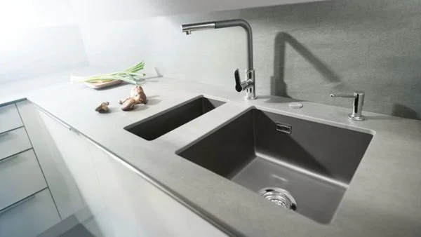 Eine dunkelgraue Unterbauspüle in einer Arbeitsplatte in beige/grau