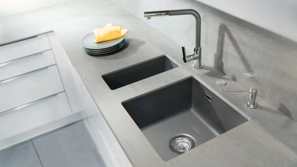 Eine dunkelgraue Unterbauspüle in einer Arbeitsplatte in beige/grau