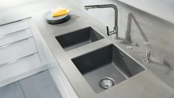 Eine dunkelgraue Unterbauspüle in einer Arbeitsplatte in beige/grau