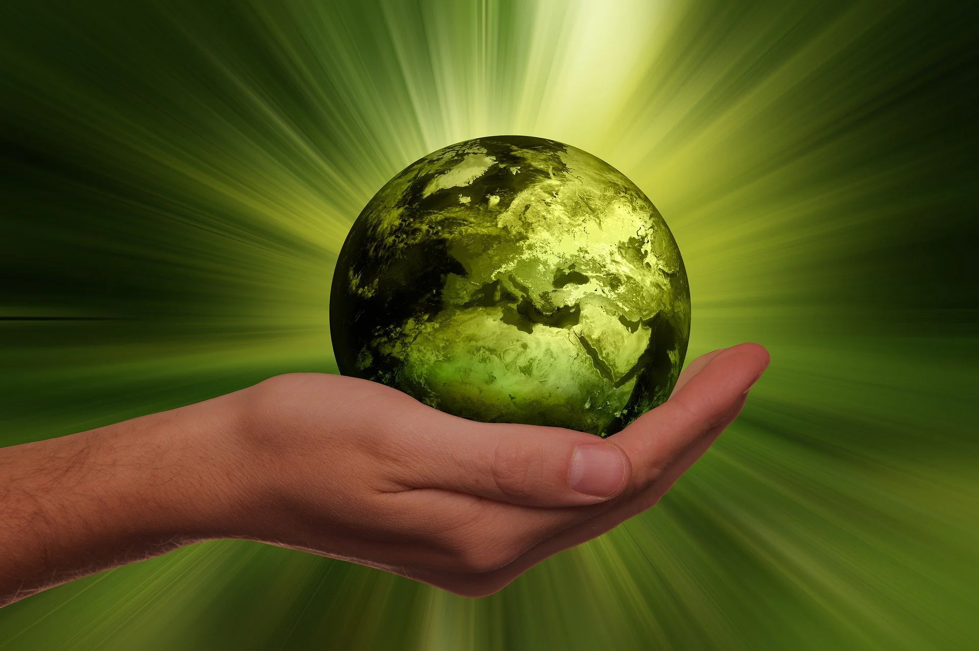 Eine Hand, die eine kleine, grüne, leuchtende Kugel in der Hand hält, diese soll die Erde symbolisieren
