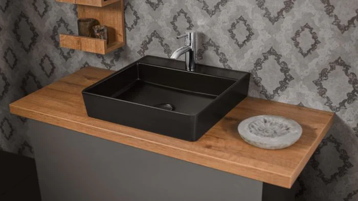 Schwarzes Waschbecken, auf einer Armatur aus Holz